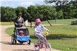 Woman Pushing a Stroller and Girl Biking
